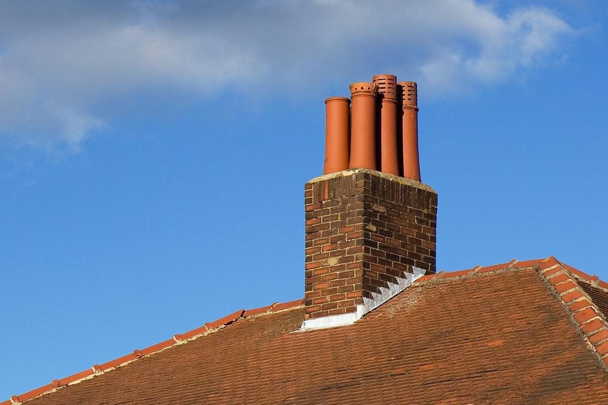 Brick chimney with terracotta pots against a blue sky